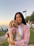 Woman holding a dog in a park with a sunset background
