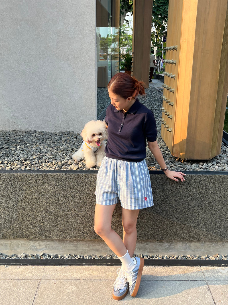 Person holding a small dog on a leash near a building entrance