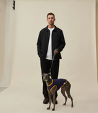 Man standing with a dog wearing a sweater in a studio setting