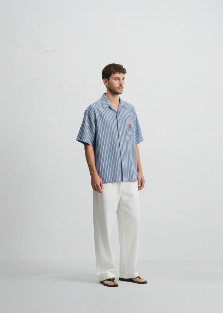 Man wearing a blue striped shirt and white pants on a light gray background