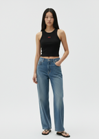 Woman wearing a black tank top and blue jeans on a white background