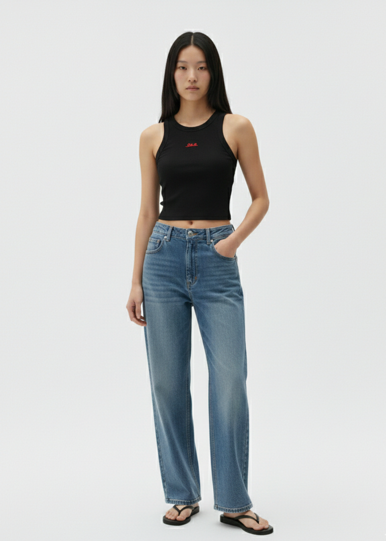 Woman wearing a black tank top and blue jeans on a white background