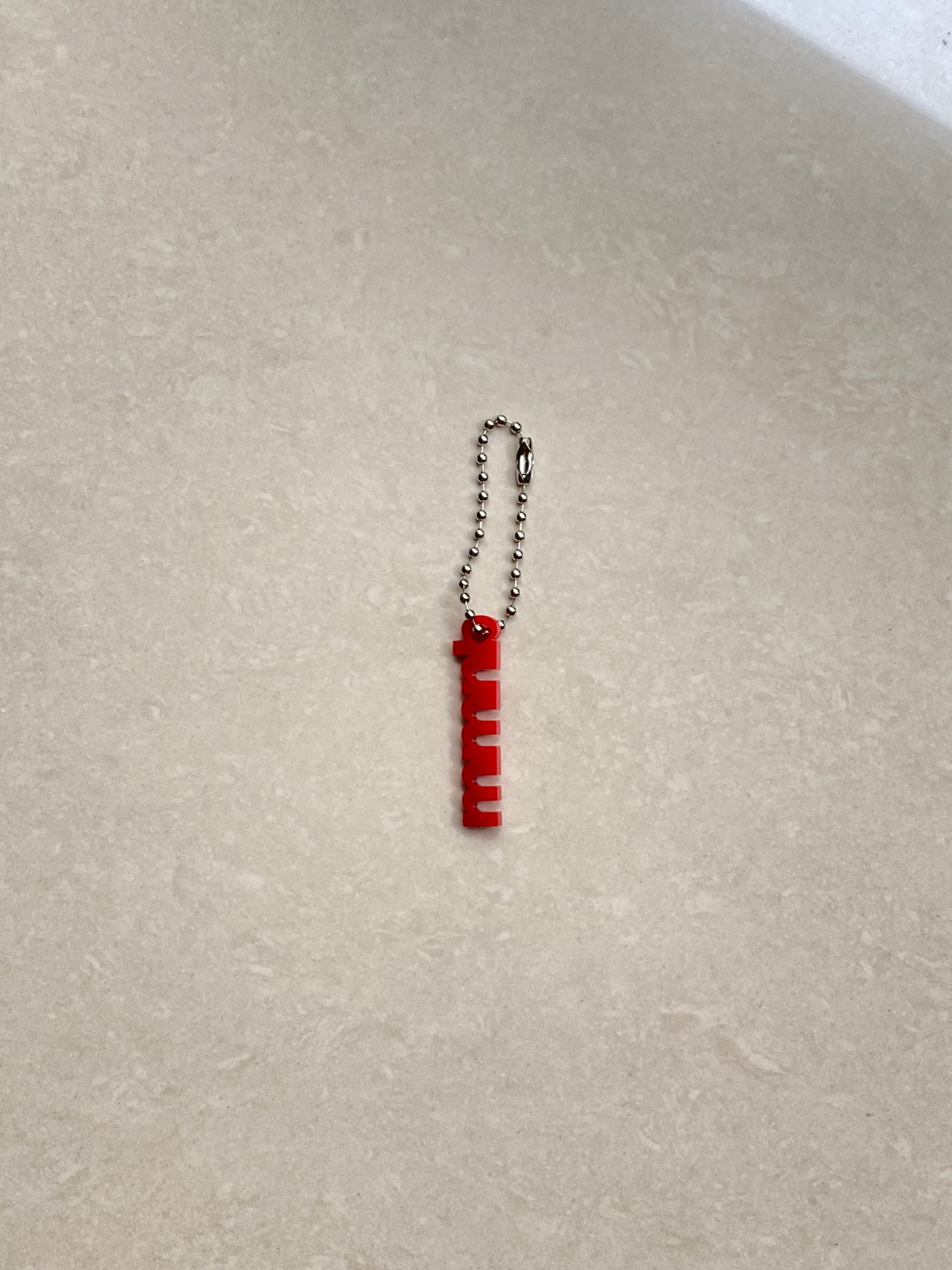 Red keychain with a metal chain on a light gray surface
