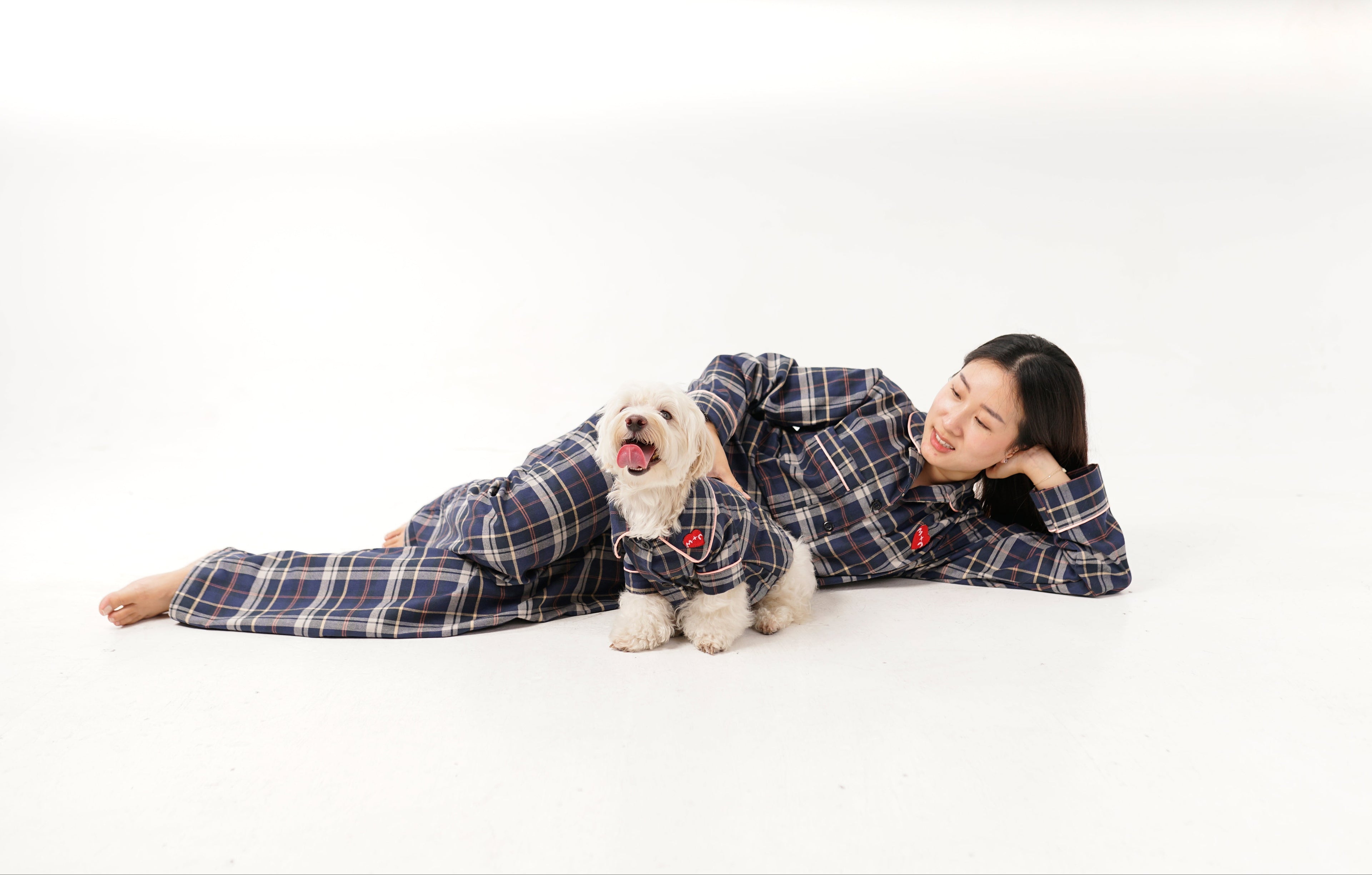 Woman and dog wearing matching plaid outfits on a white background