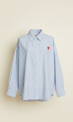 Blue striped shirt with a red heart emblem on a beige background