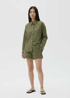 Person wearing a green ribbed shirt and shorts on a white background