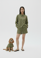 Woman and dog wearing matching green outfits on a white background