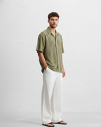 Man wearing a green striped shirt and white pants on a white background