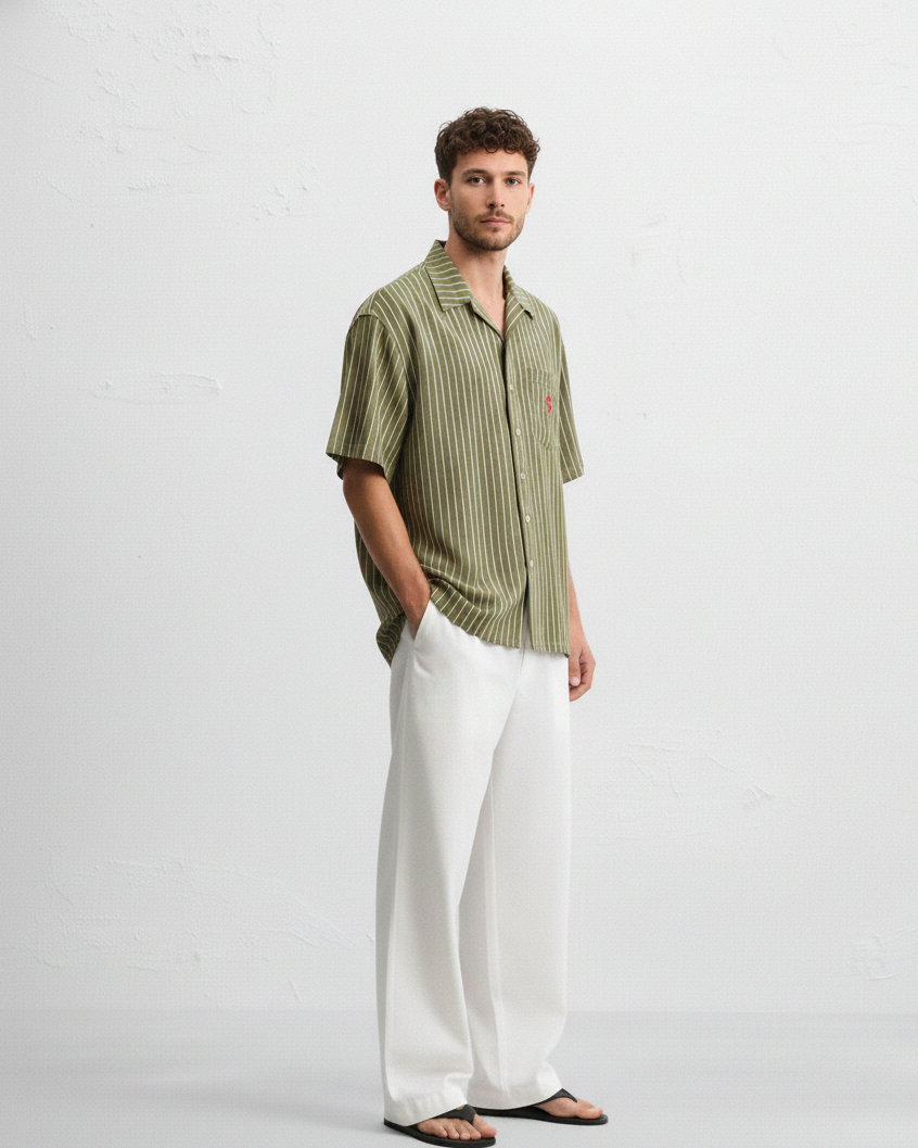 Man wearing a green striped shirt and white pants on a white background