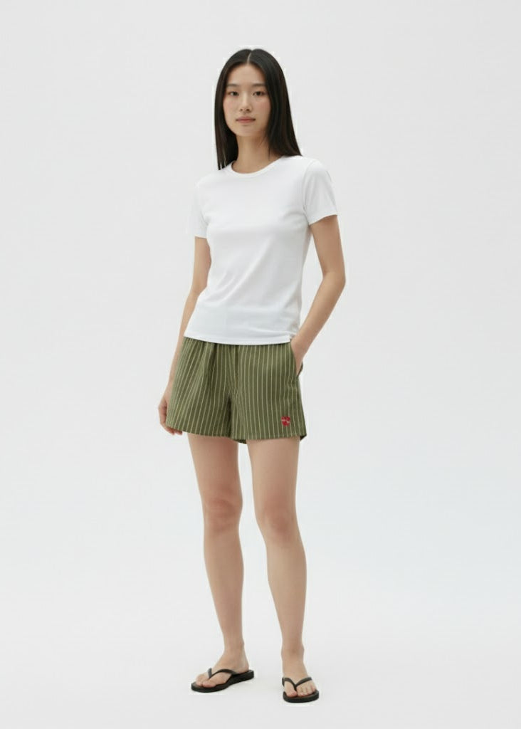 Person wearing a white t-shirt and green shorts on a plain background