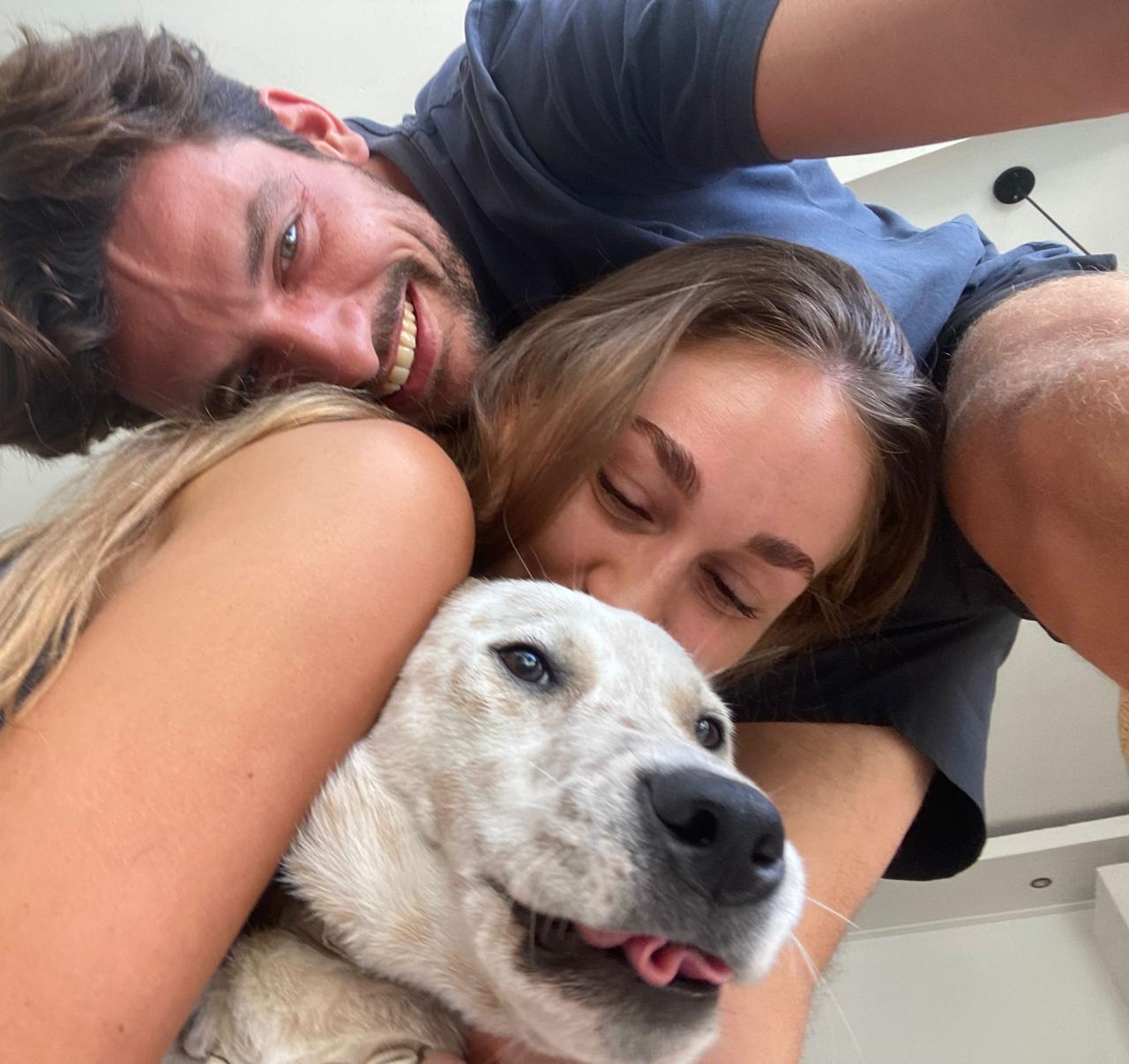 Two people lying on a bed with a dog