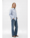 Woman wearing a light blue striped shirt and jeans on a white background