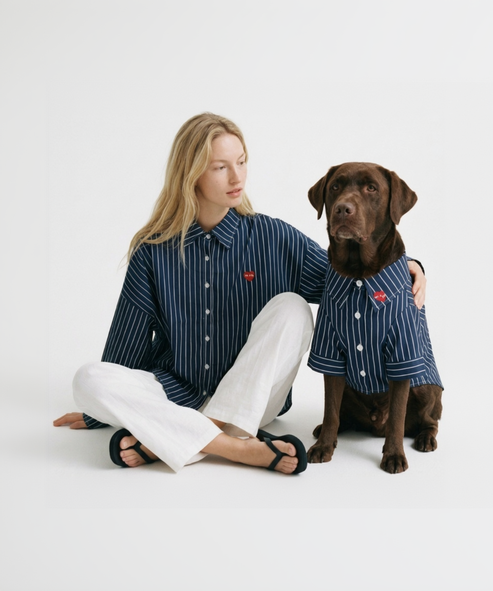 Woman and dog wearing matching blue striped shirts on a white background